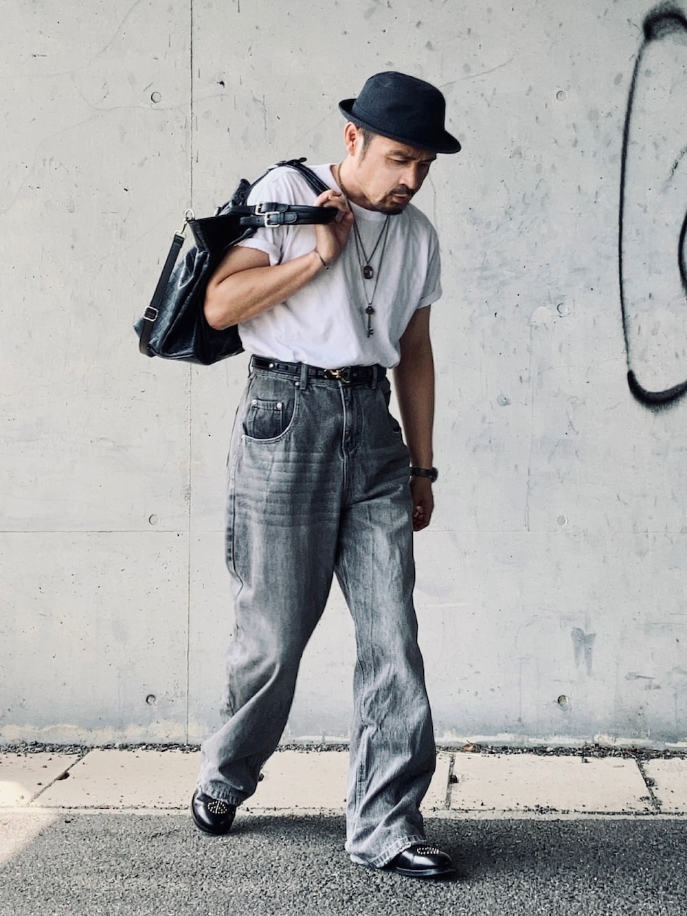 ホワイト系のTシャツ/カットソー、グレー系のデニムパンツ、ブラック系のドレスシューズを着用したメンズの秋コーディネートの2枚目の写真