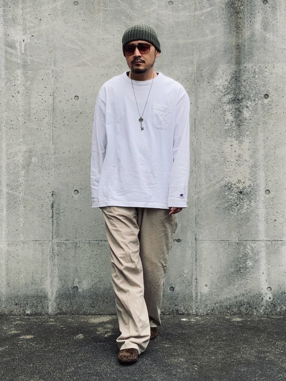 ホワイト系のTシャツ/カットソー、ベージュ系のスラックス、ブラウン系のスリッポンを着用したメンズの春コーディネートの2枚目の写真