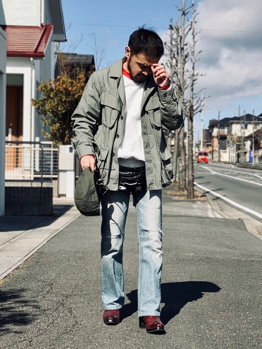 ホワイト系のスウェット、グリーン系のミリタリージャケット、ブルー系のデニムパンツを着用したメンズの冬コーディネートの2枚目の写真