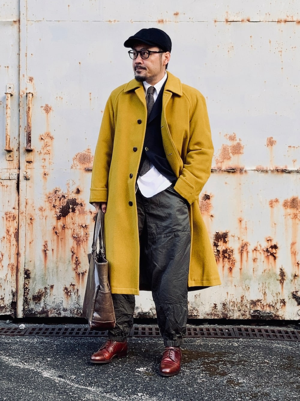 イエロー系のステンカラーコート、グリーン系のその他パンツ、ブラウン系のドレスシューズを着用したメンズの冬コーディネートの5枚目の写真