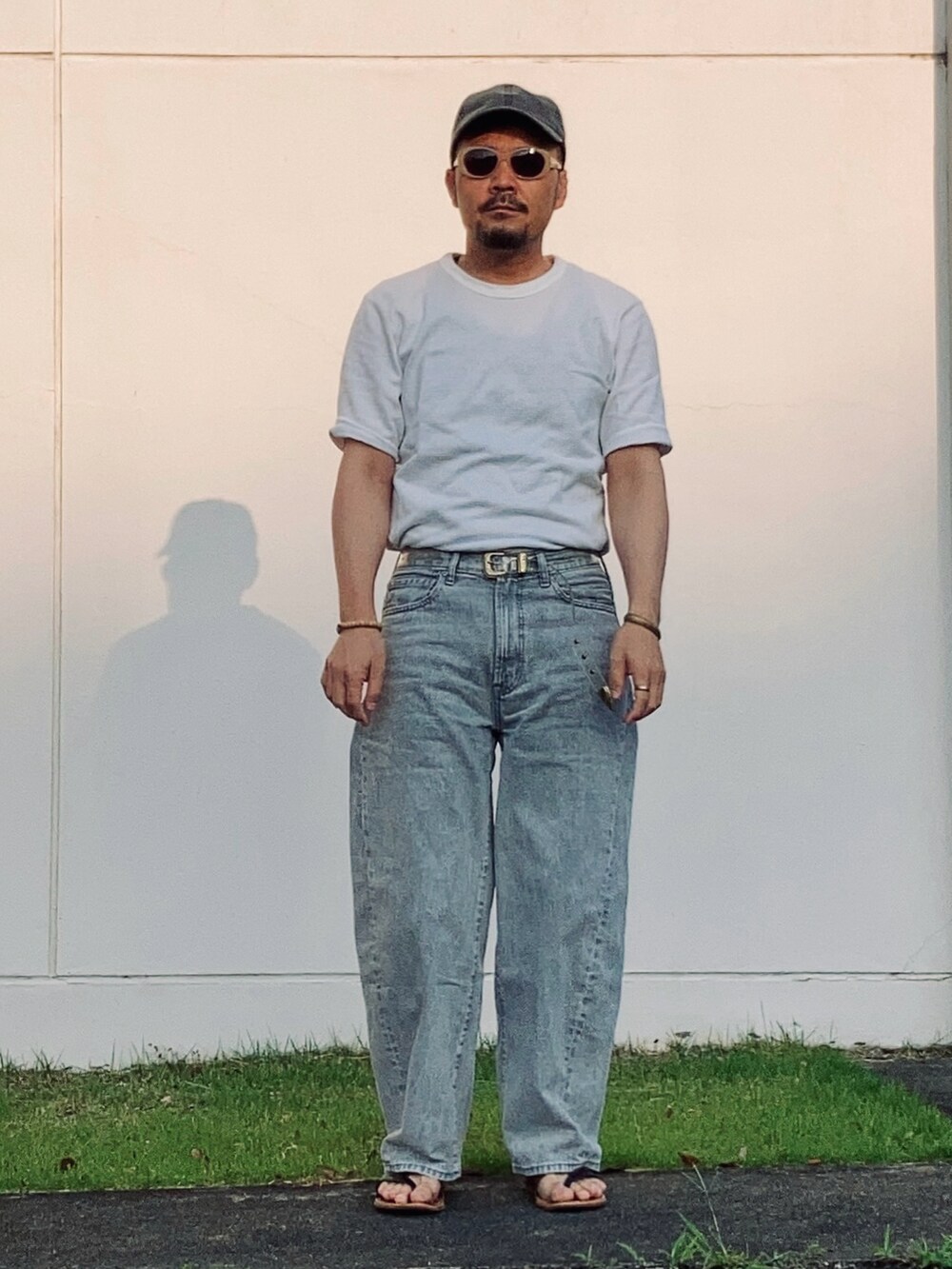 グレー系のデニムパンツ、ホワイト系のTシャツ/カットソー、ブラウン系のサンダルを着用したメンズの夏コーディネートの2枚目の写真