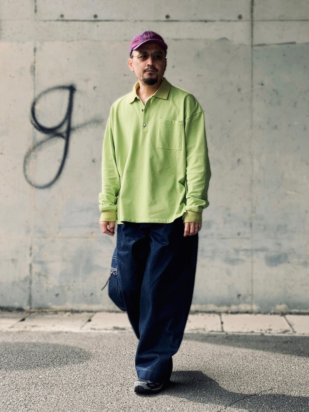 グリーン系のポロシャツ、ブルー系のデニムパンツ、ブラック系のスニーカーを着用したメンズの春コーディネートの2枚目の写真