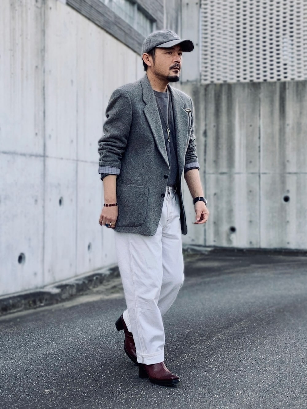 グレー系のテーラードジャケット、グリーン系のニット/セーター、ホワイト系のデニムパンツを着用したメンズの春コーディネートの2枚目の写真