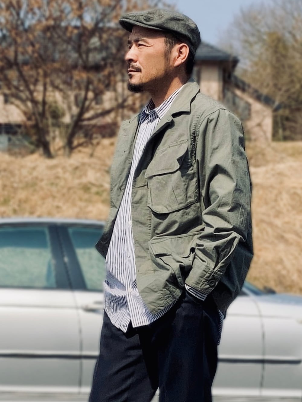 ブルー系のシャツ/ブラウス、グリーン系のミリタリージャケット、ブルー系のスラックスを着用したメンズの春コーディネートの3枚目の写真