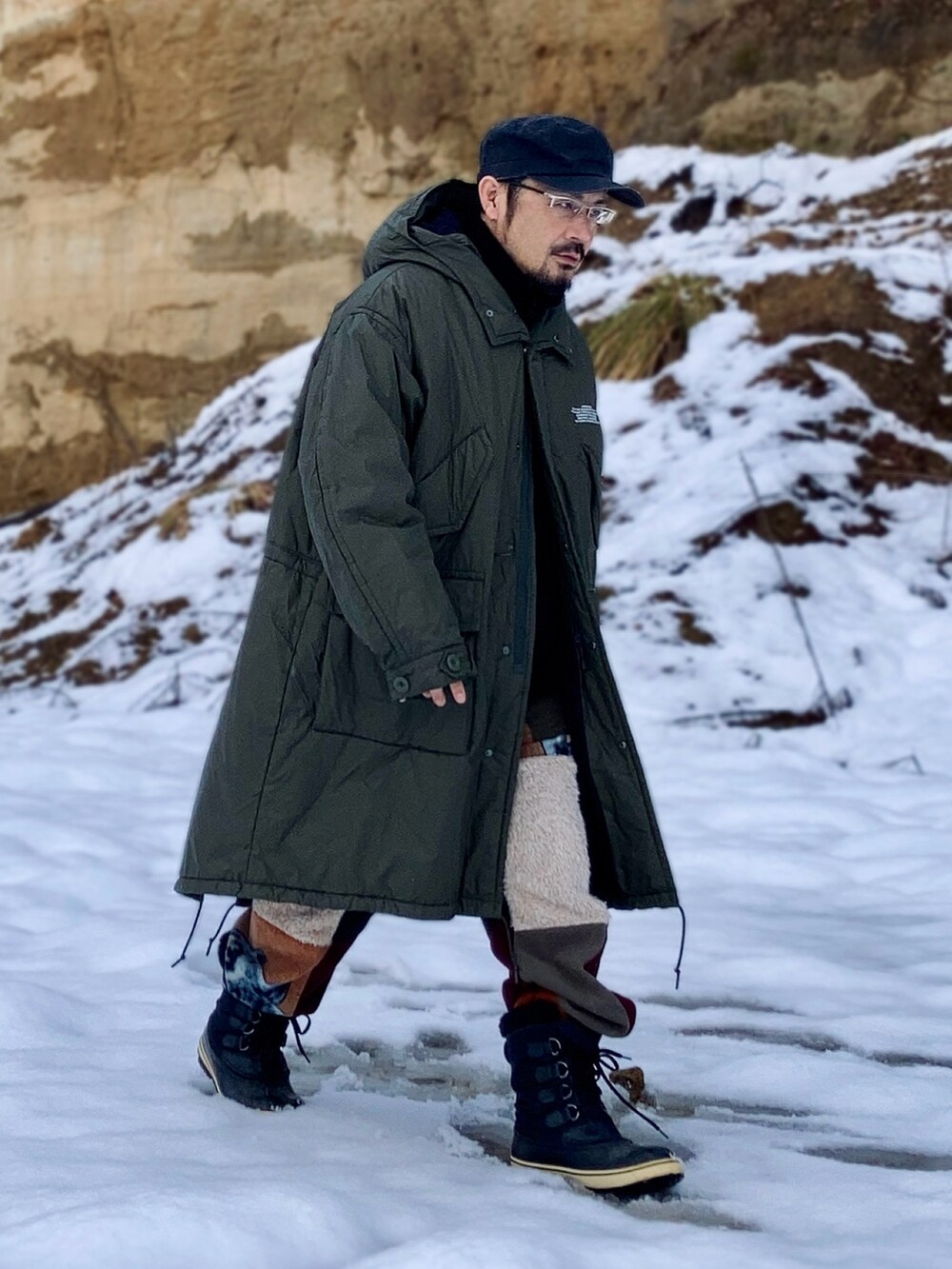 グリーン系のミリタリージャケット、ブラック系のその他アウター、その他のスウェットパンツを着用したメンズの冬コーディネートの4枚目の写真