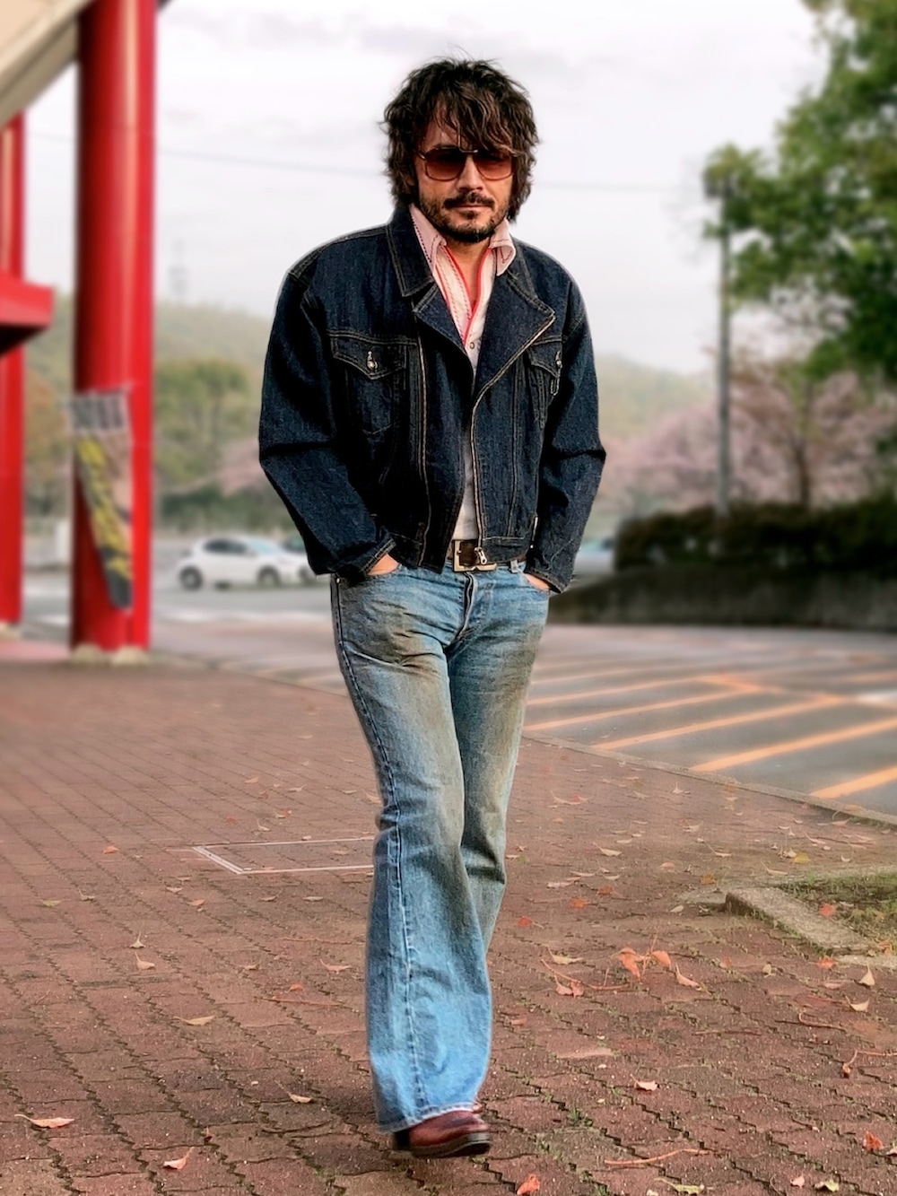 ホワイト系のポロシャツ、ブルー系のライダースジャケット、ブルー系のデニムパンツを着用したメンズの春コーディネートの2枚目の写真