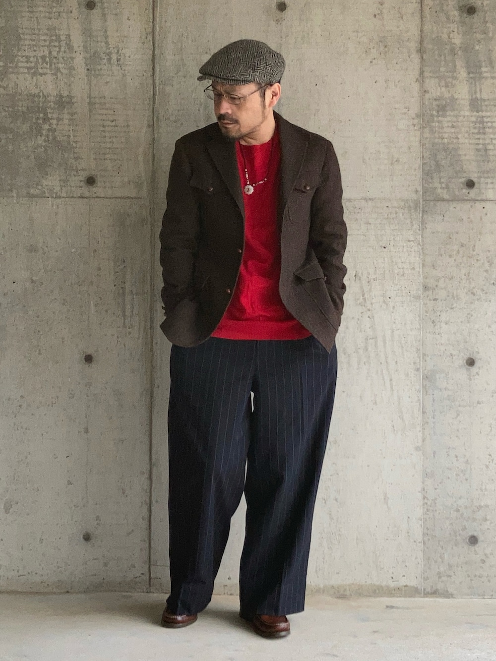 レッド系のニット/セーター、ブラウン系のテーラードジャケット、ブルー系のスラックスを着用したメンズの冬コーディネートの3枚目の写真