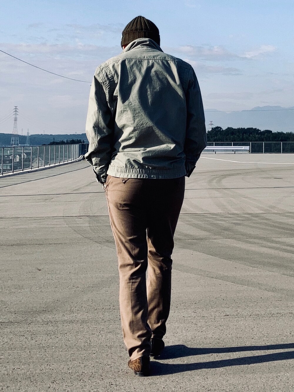 グレー系のTシャツ/カットソー、グリーン系のミリタリージャケット、グリーン系のスラックスを着用したメンズの秋コーディネートの3枚目の写真