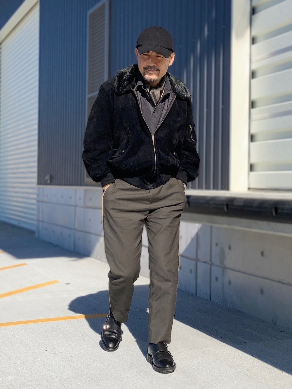 ブラック系のポロシャツ、ブラック系のブルゾン、グリーン系のスラックスを着用したメンズの秋コーディネートの4枚目の写真