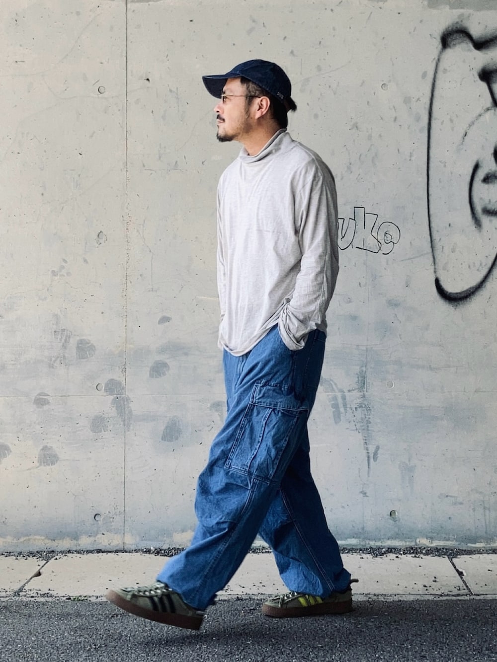 グレー系のTシャツ/カットソー、ブルー系のカーゴパンツ、グリーン系のスニーカーを着用したメンズの春コーディネートの3枚目の写真