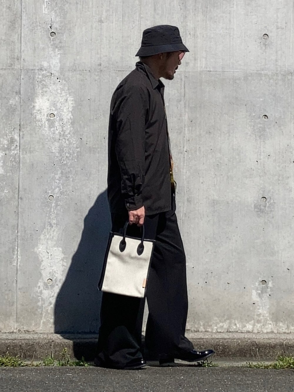 ブラック系のシャツ/ブラウス、ブラック系のスラックス、ブラック系のブーツを着用したメンズの春コーディネートの2枚目の写真