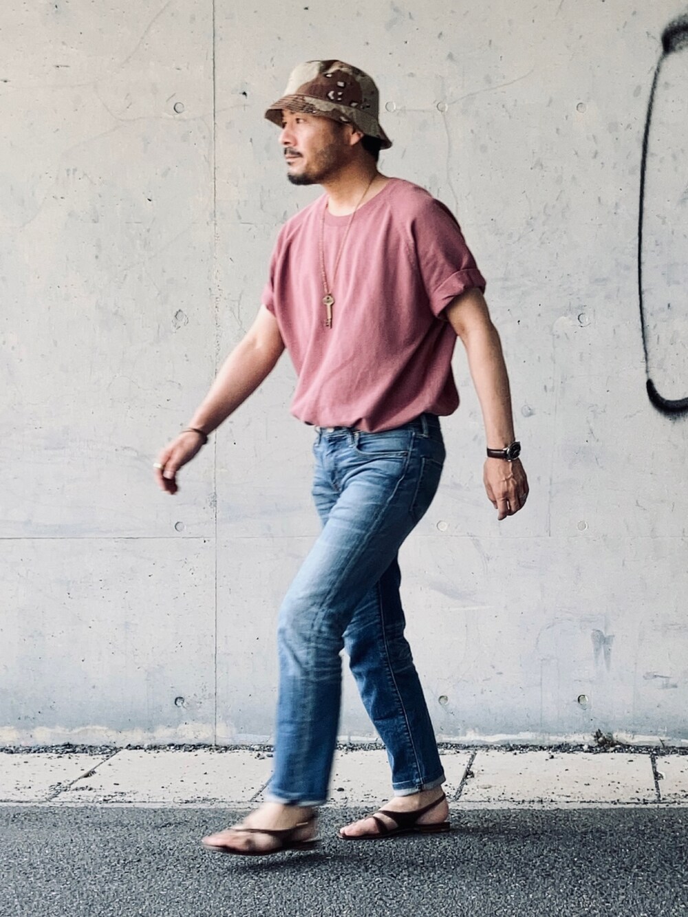ピンク系のTシャツ/カットソー、ブルー系のデニムパンツ、ブラウン系のサンダルを着用したメンズの夏コーディネートの3枚目の写真
