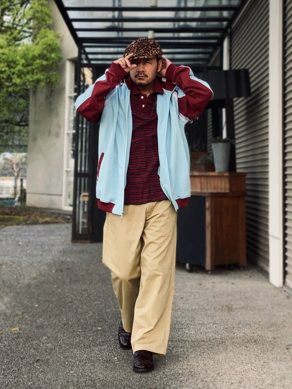 ベージュ系のチノパンツ、レッド系のポロシャツ、ブルー系のその他アウターを着用したメンズの春コーディネートの3枚目の写真