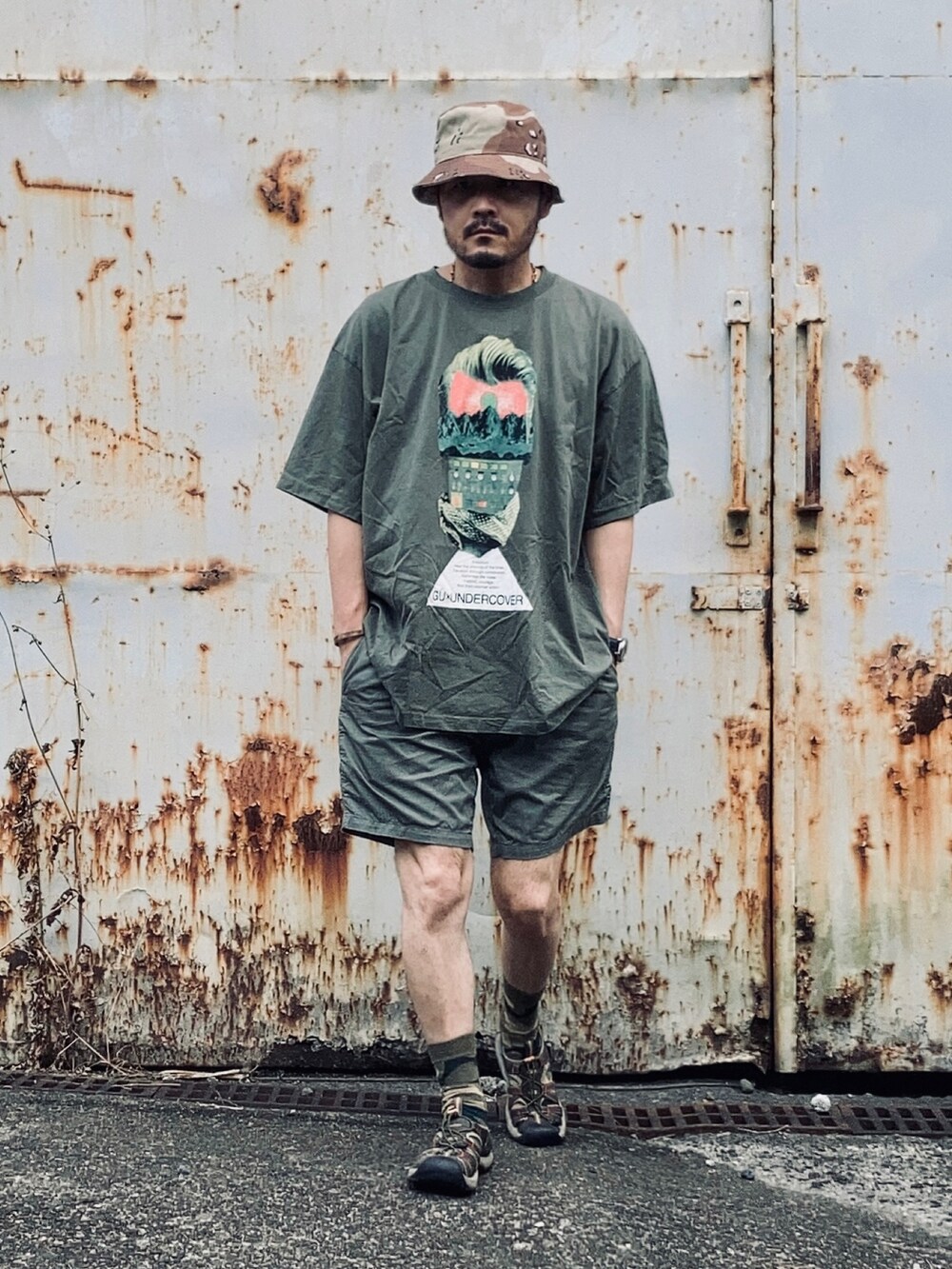 グリーン系のTシャツ/カットソー、グリーン系のチノパンツ、ブラック系のサンダルを着用したメンズの夏コーディネートの2枚目の写真