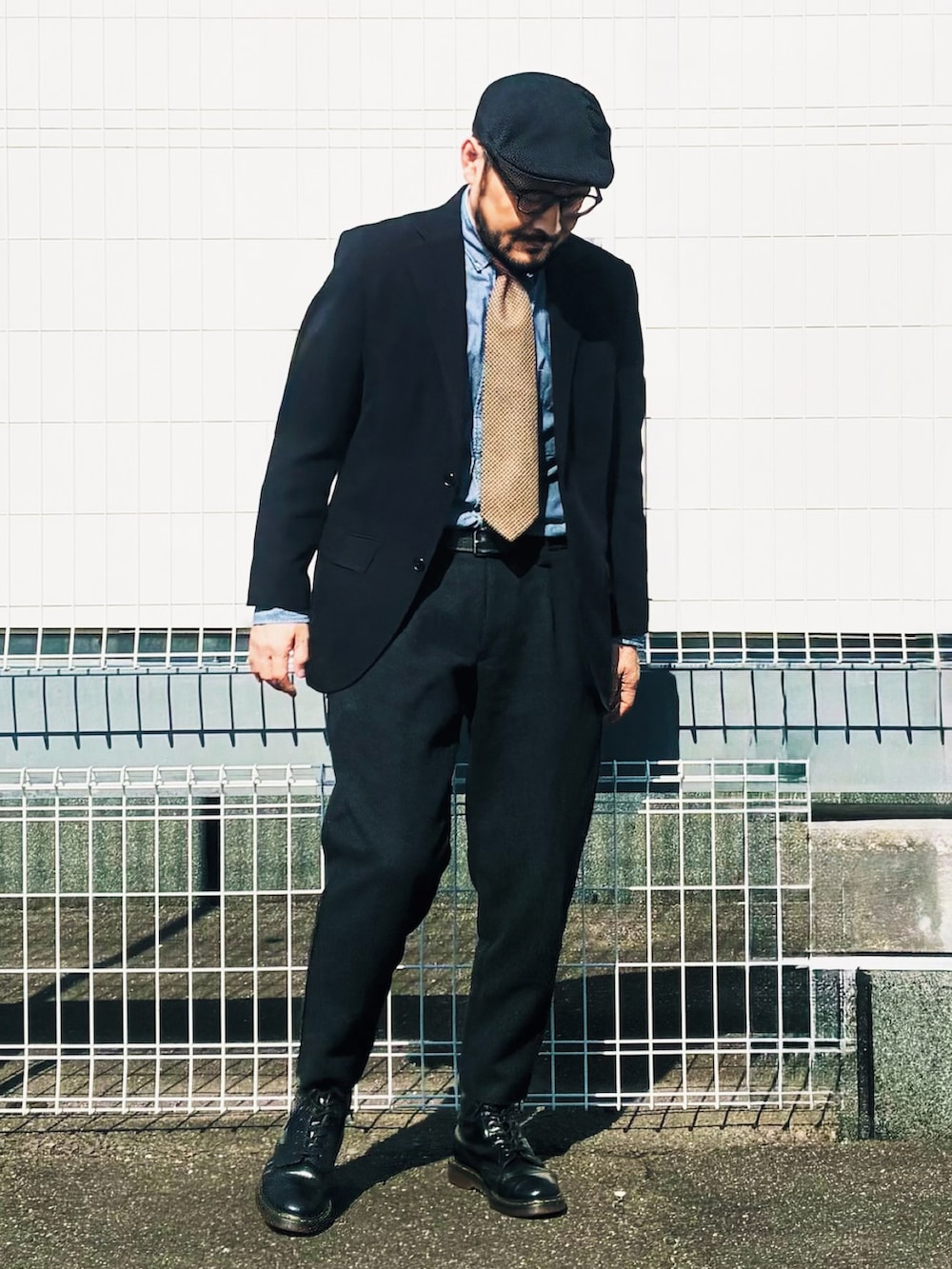 ブラック系のテーラードジャケット、ブラック系のスラックス、ブラック系のブーツを着用したメンズの春コーディネートの2枚目の写真