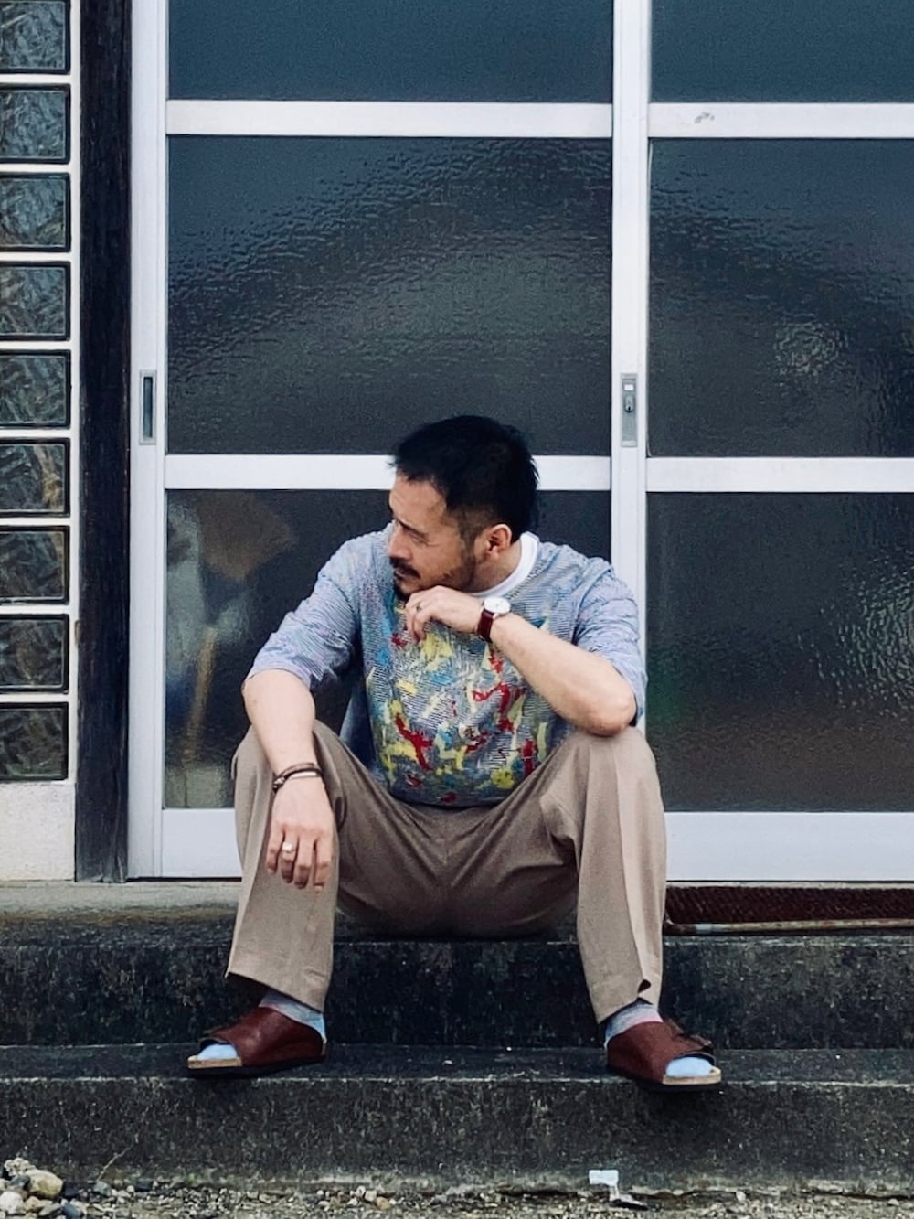 ホワイト系のTシャツ/カットソー、ベージュ系のスラックス、ブラウン系のサンダルを着用したメンズの春コーディネートの2枚目の写真