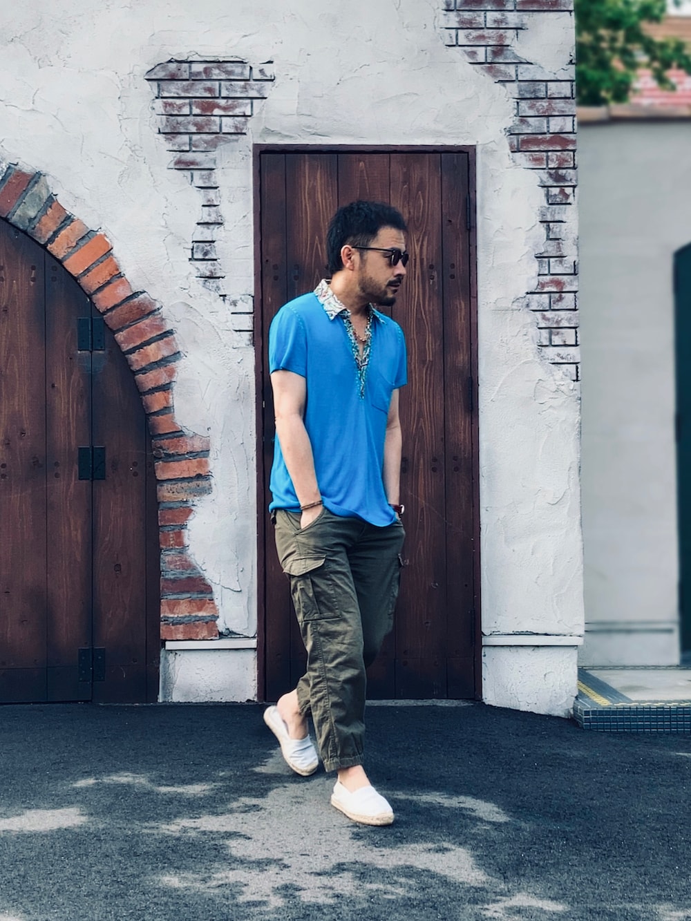 グリーン系のパンツ、ホワイト系のスリッポン、ブルー系のポロシャツを着用したメンズの夏コーディネートの2枚目の写真