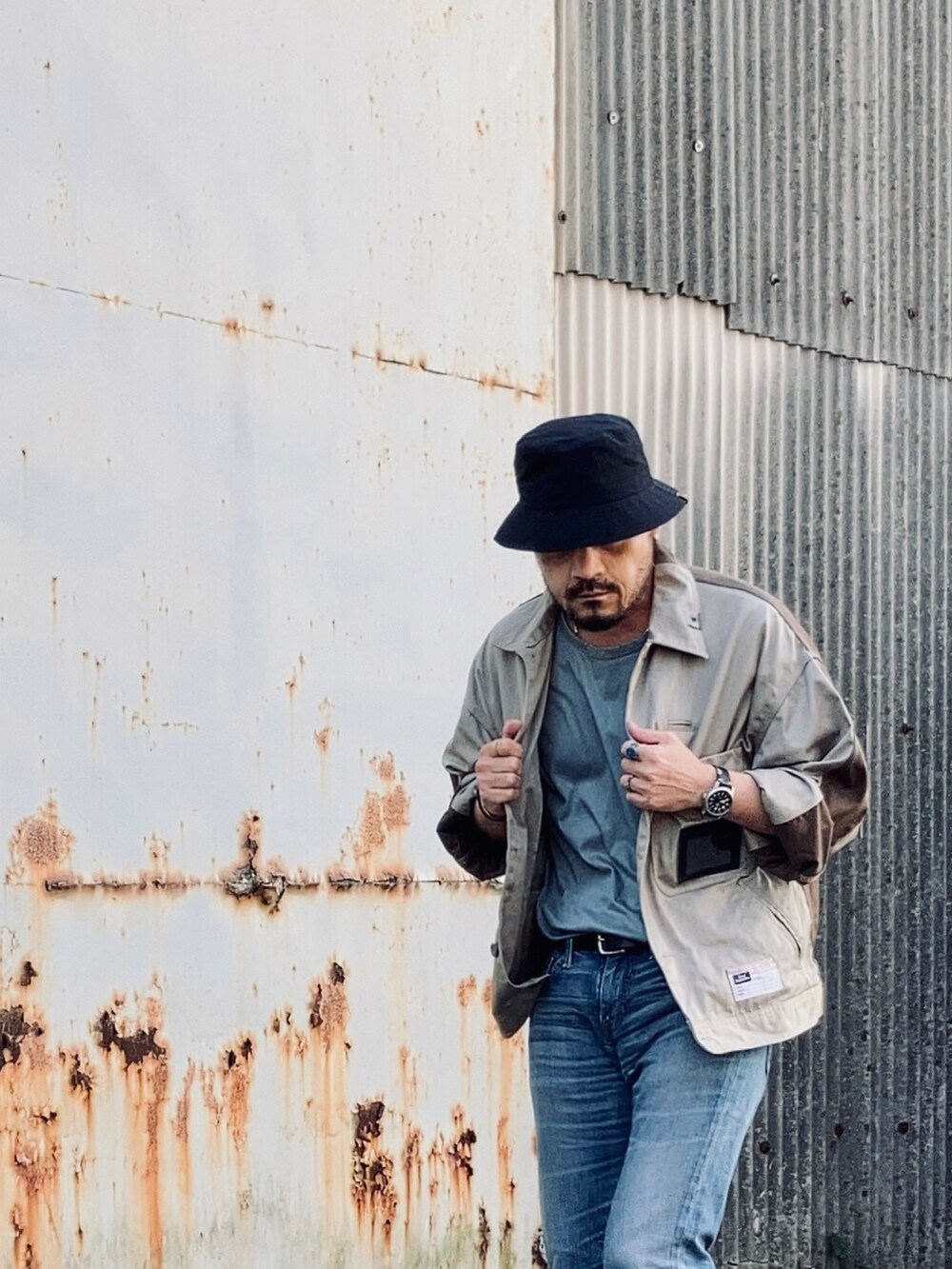 グリーン系のTシャツ/カットソー、ベージュ系のその他アウター、ブルー系のデニムパンツを着用したメンズの春コーディネートの4枚目の写真