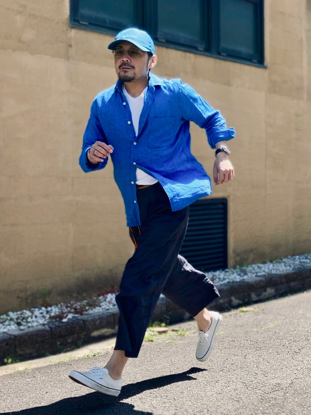 ホワイト系のTシャツ/カットソー、ブルー系のシャツ/ブラウス、グレー系のスラックスを着用したメンズの春コーディネートの2枚目の写真