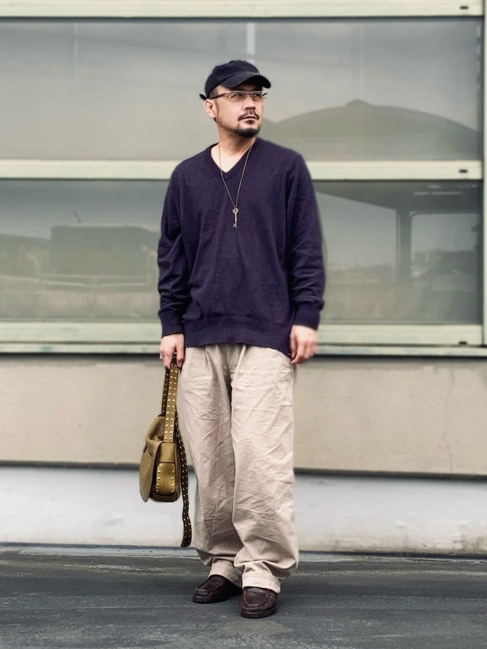 パープル系のニット/セーター、ベージュ系のスラックス、ブラウン系のブーツを着用したメンズの春コーディネートの2枚目の写真