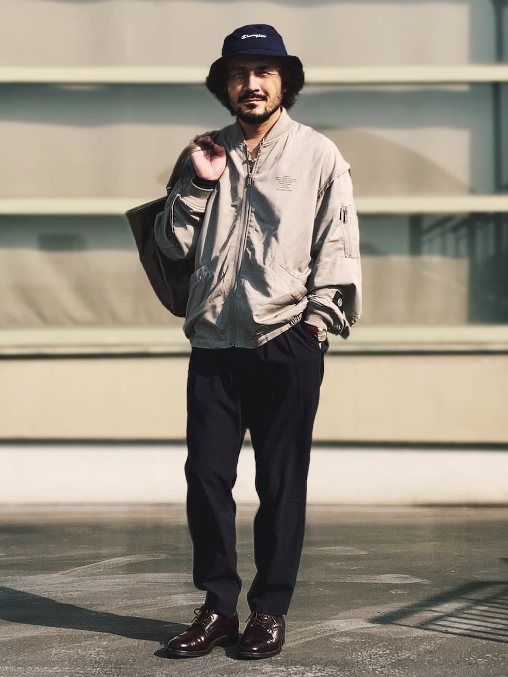 ベージュ系のMA-1、ブルー系のスラックス、レッド系のドレスシューズを着用したメンズの春コーディネートの3枚目の写真