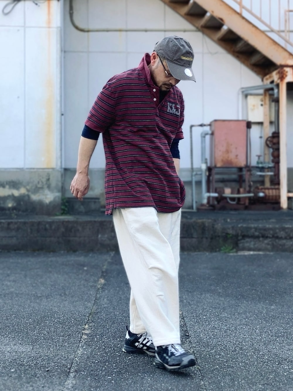 グレー系のスウェットパンツ、レッド系のポロシャツ、ブラック系のスニーカーを着用したメンズの春コーディネートの3枚目の写真