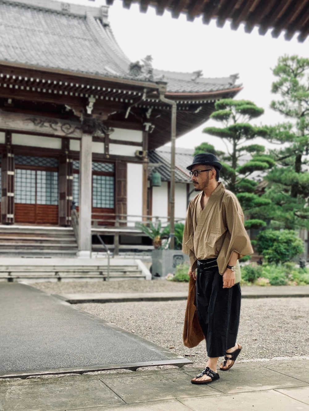 ブラック系のサンダル、イエロー系のボディバッグ/ウエストポーチ、ブラウン系のトートバッグを着用したメンズの夏コーディネートの5枚目の写真