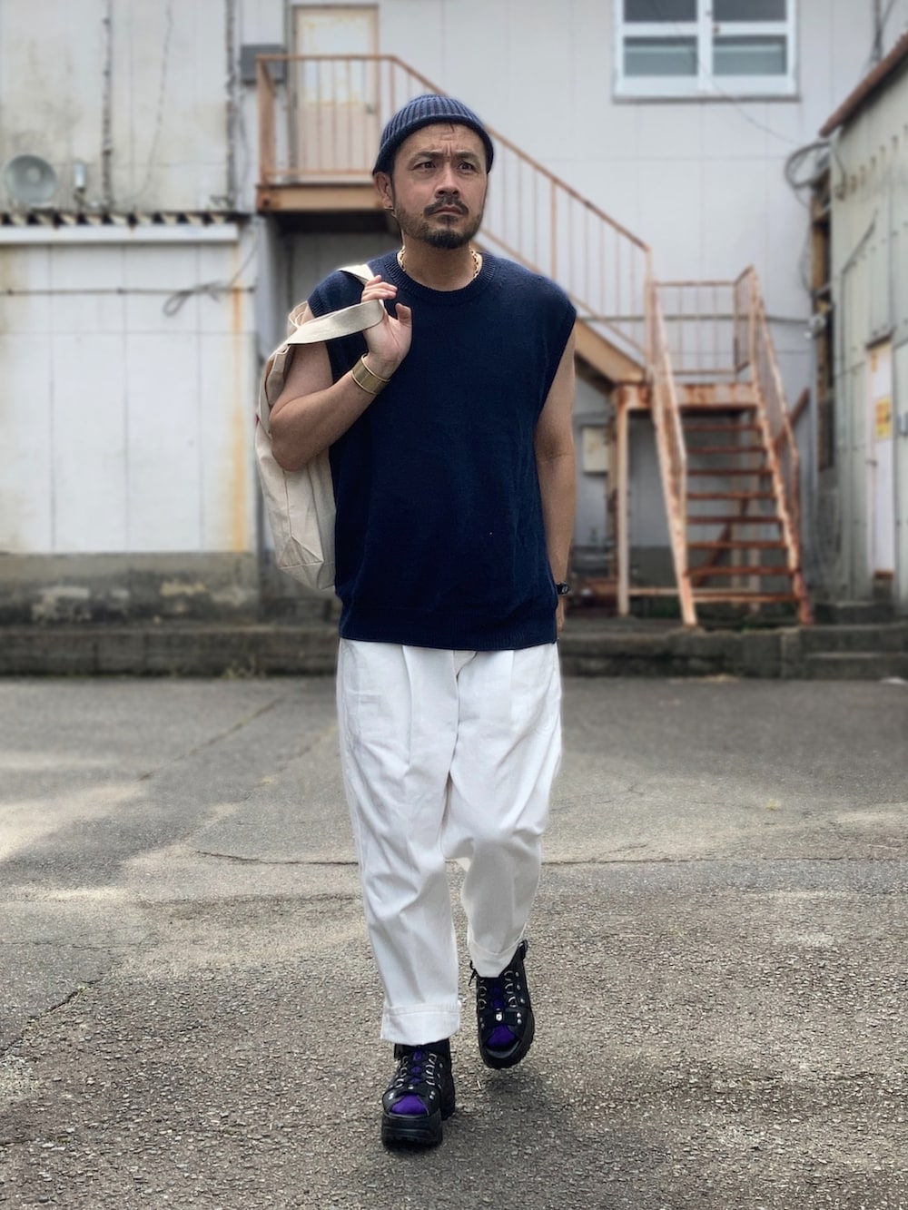 ブルー系のベスト、ホワイト系のスラックス、ブラック系のサンダルを着用したメンズの夏コーディネートの3枚目の写真