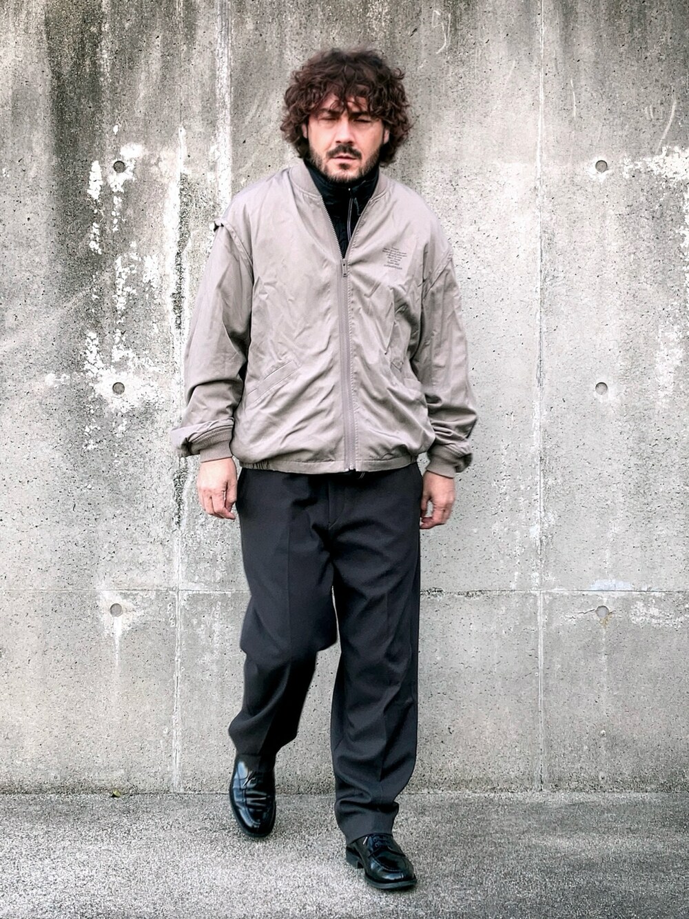 ベージュ系のMA-1、ブラック系のベスト、グレー系のスラックスを着用したメンズの冬コーディネートの4枚目の写真