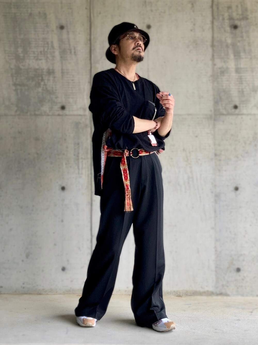 ブラック系のTシャツ/カットソー、ブラック系のスラックス、レッド系のスニーカーを着用したメンズの春コーディネートの3枚目の写真