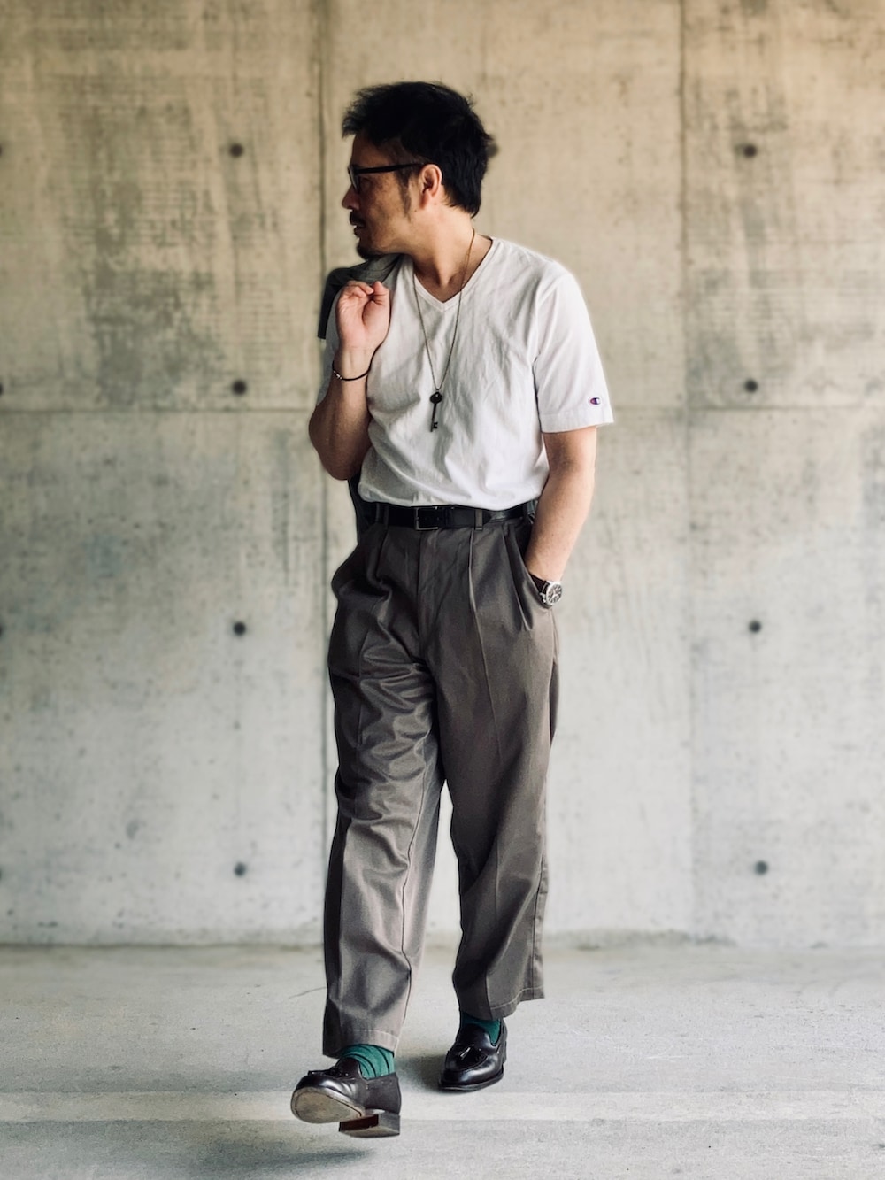 ホワイト系のTシャツ/カットソー、グレー系のスラックス、ブラウン系のローファーを着用したメンズの春コーディネートの2枚目の写真