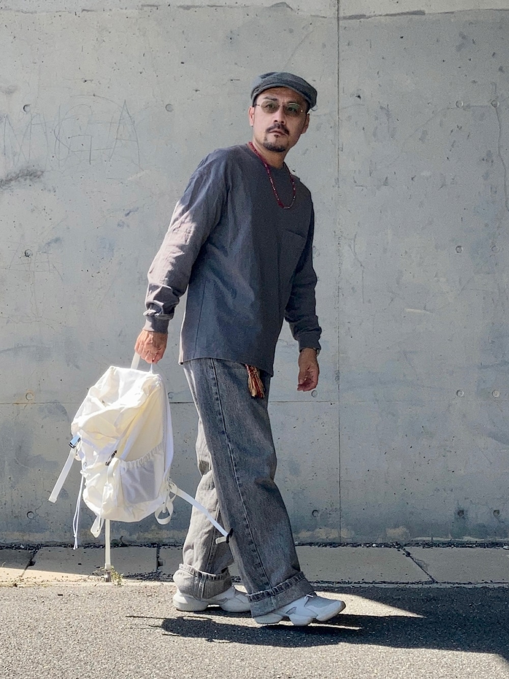 グレー系のTシャツ/カットソー、グレー系のデニムパンツ、グレー系のスニーカーを着用したメンズの秋コーディネートの2枚目の写真