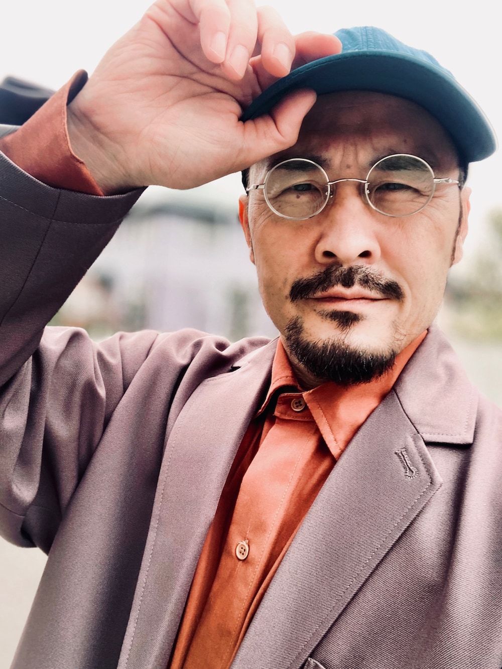 オレンジ系のシャツ/ブラウス、グレー系のセットアップ、ブラック系のスニーカーを着用したメンズの春コーディネートの5枚目の写真