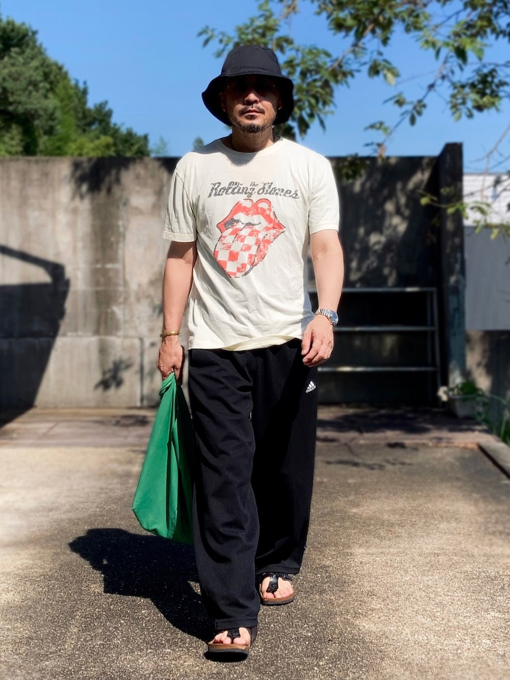 イエロー系のTシャツ/カットソー、ブラック系のパンツ、ブラック系のサンダルを着用したメンズの夏コーディネートの3枚目の写真