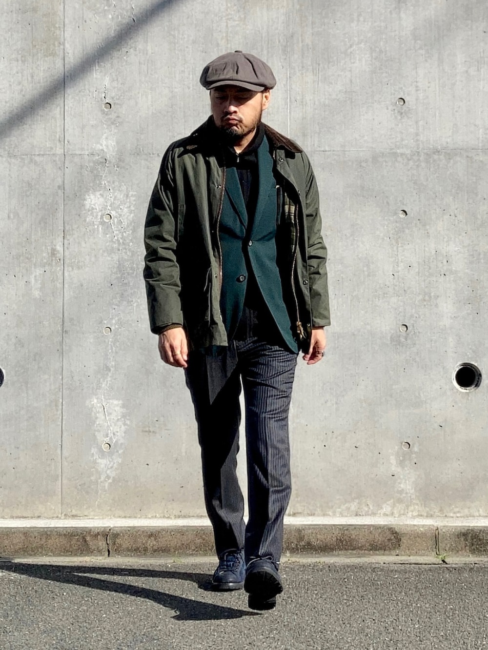 ブラック系のニット/セーター、グリーン系のテーラードジャケット、グレー系のスラックスを着用したメンズの冬コーディネートの3枚目の写真