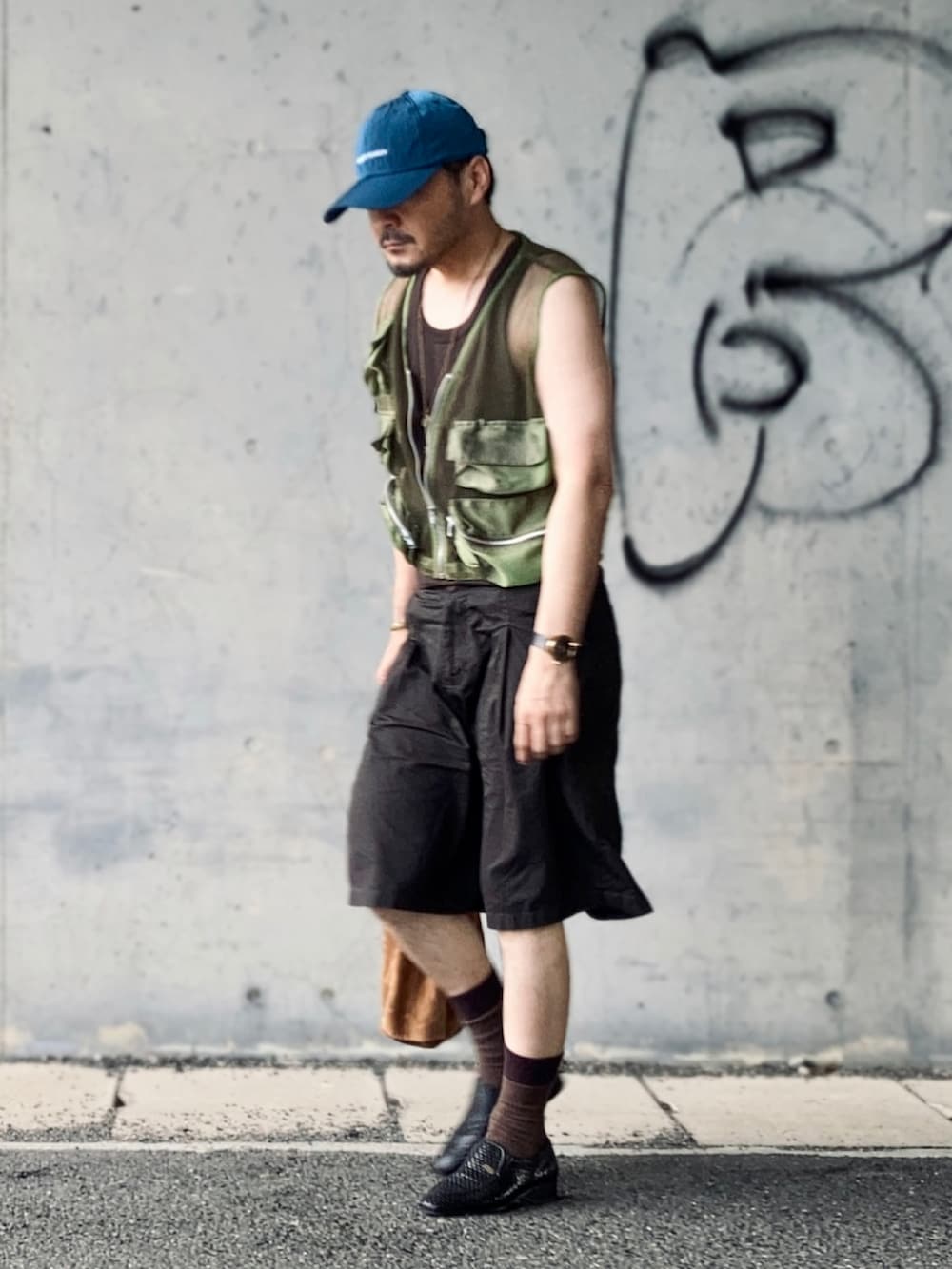 ブラウン系のタンクトップ、グリーン系のベスト、ブラウン系のパンツを着用したメンズの夏コーディネートの2枚目の写真