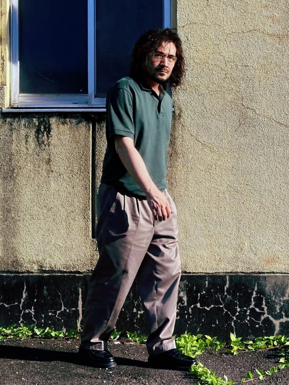 グリーン系のポロシャツ、グレー系のスラックス、ブラック系のローファーを着用したメンズの夏コーディネートの2枚目の写真