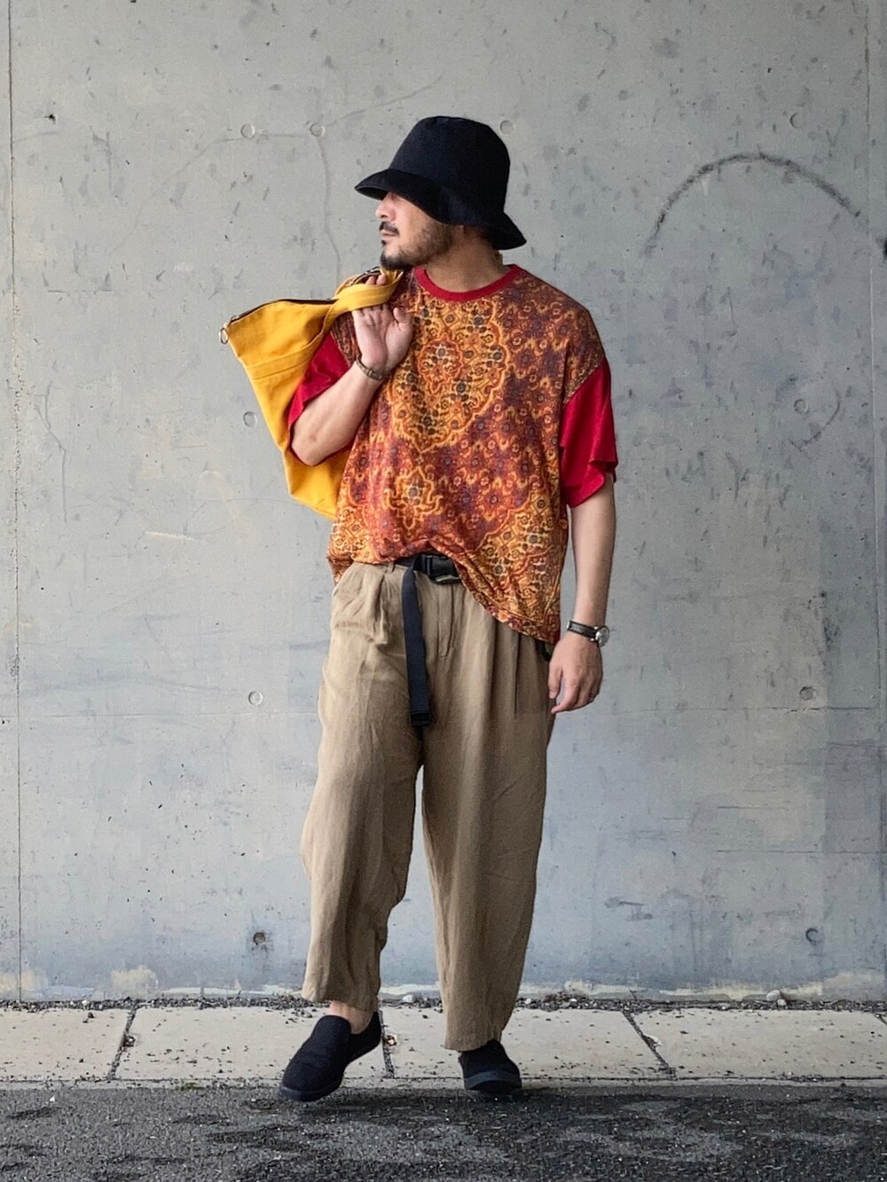 レッド系のTシャツ/カットソー、ベージュ系のその他パンツ、ブラック系のスリッポンを着用したメンズの春コーディネートの2枚目の写真