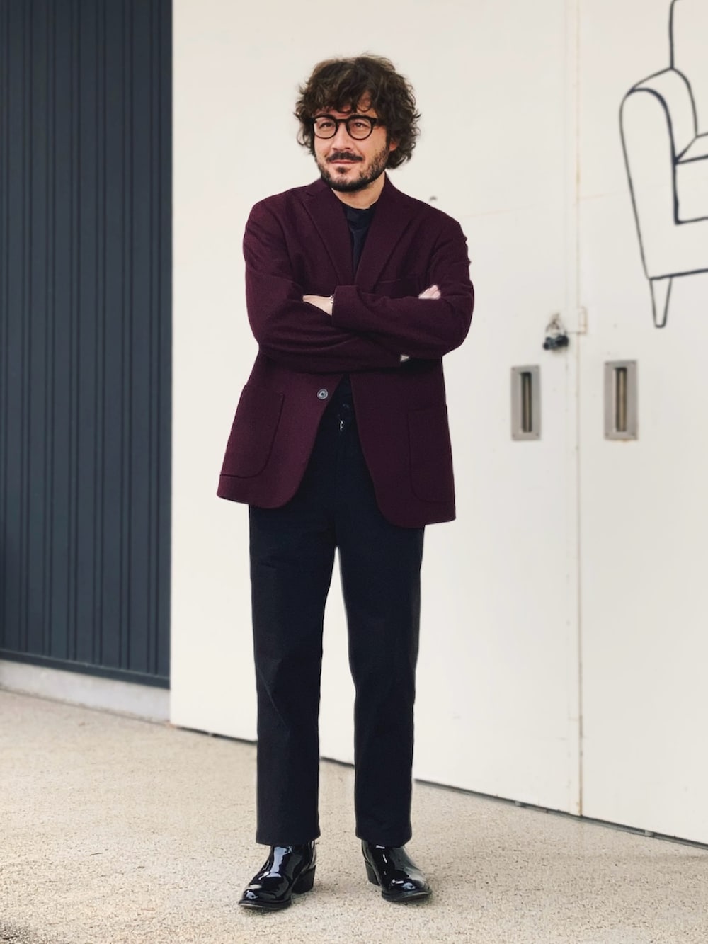 レッド系のテーラードジャケット、ブラック系のパンツ、ブラック系のブーツを着用したメンズの秋コーディネートの2枚目の写真