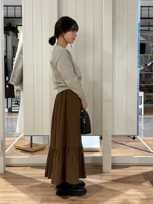 グレー系のニット/セーター、ブラウン系のスカート、ブラック系のブーツを着用したレディースの冬コーディネートの3枚目の写真