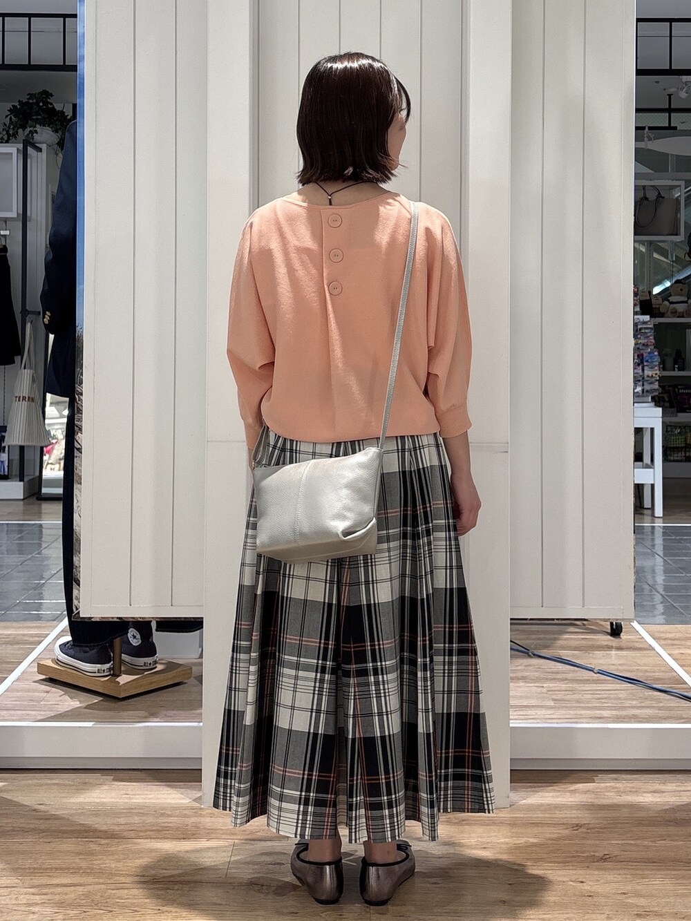 レッド系のスカート、オレンジ系のニット/セーター、シルバー系のショルダーバッグを着用したレディースの春コーディネートの3枚目の写真