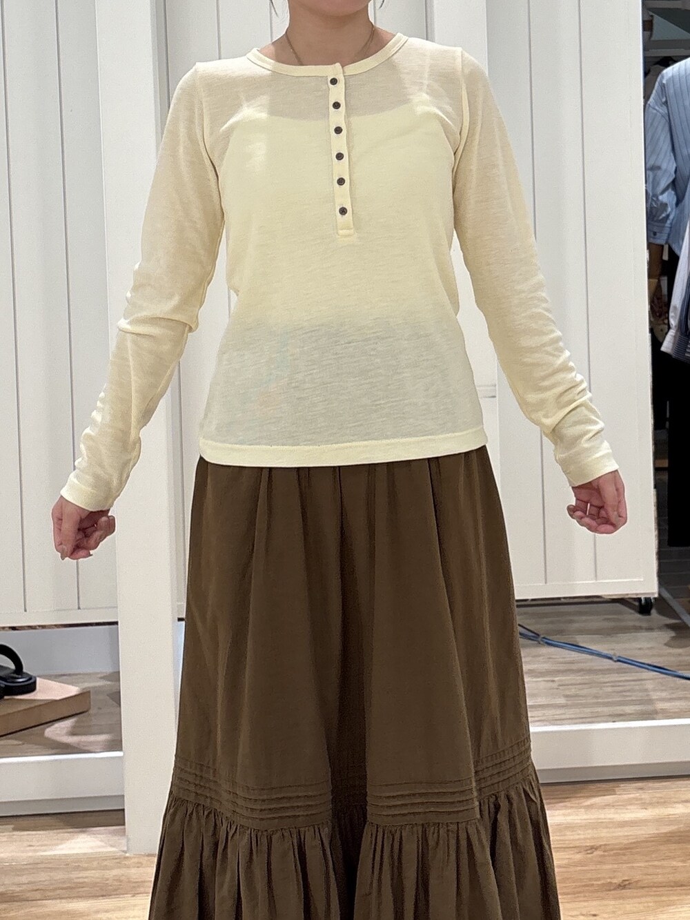 イエロー系のTシャツ/カットソー、ブラウン系のスカート、ブラック系のパンプスを着用したレディースの秋コーディネートの5枚目の写真