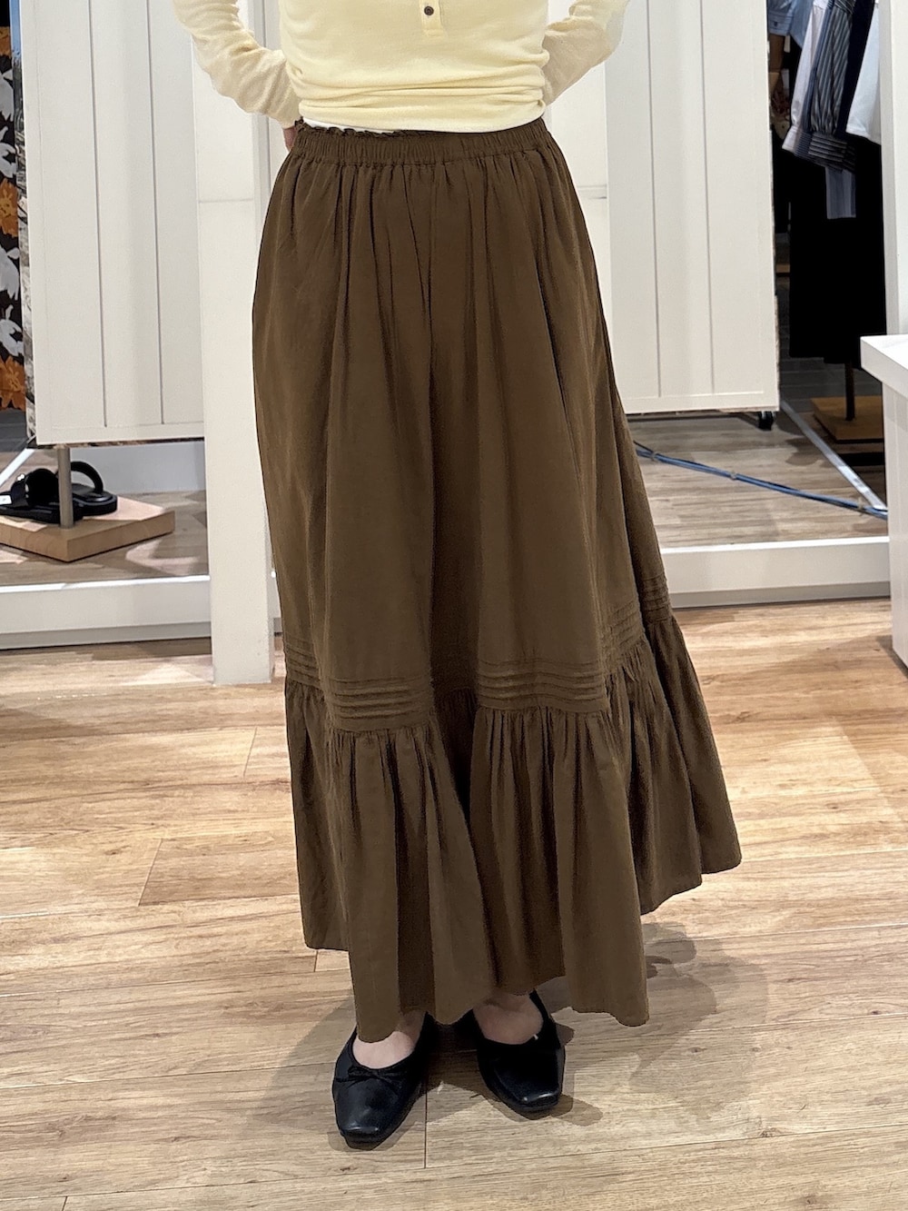 イエロー系のTシャツ/カットソー、ブラウン系のスカート、ブラック系のパンプスを着用したレディースの秋コーディネートの7枚目の写真