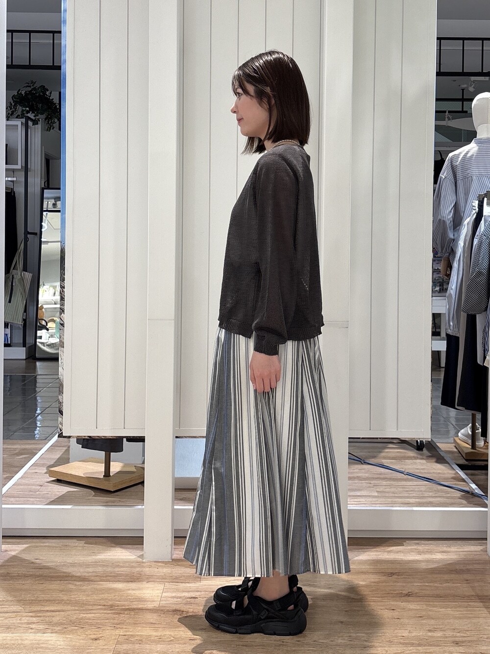 ホワイト系のスカート、ベージュ系のトートバッグ、ブラック系のサンダルを着用したレディースの春コーディネートの2枚目の写真