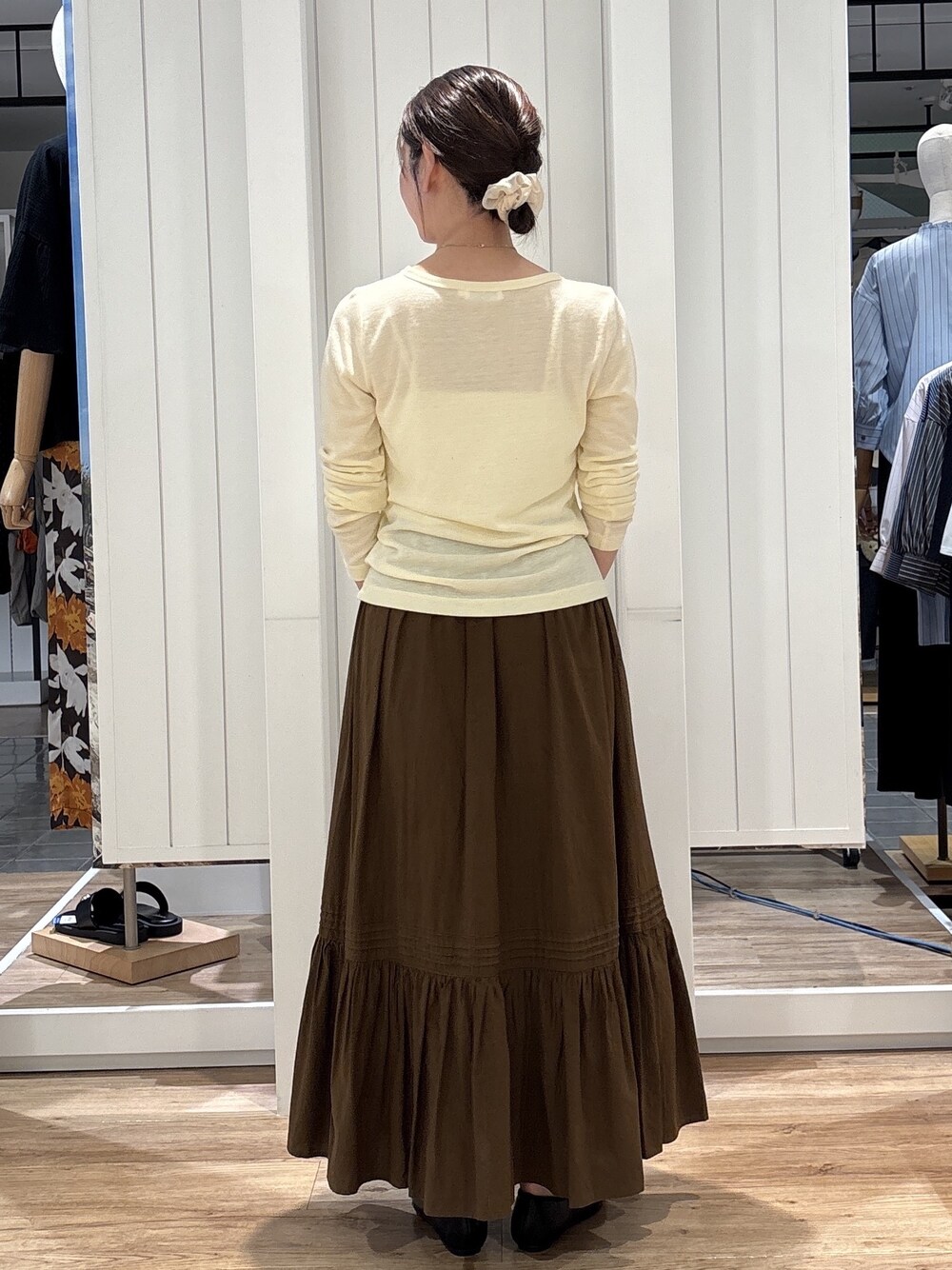 イエロー系のTシャツ/カットソー、ブラウン系のスカート、ブラック系のパンプスを着用したレディースの秋コーディネートの3枚目の写真