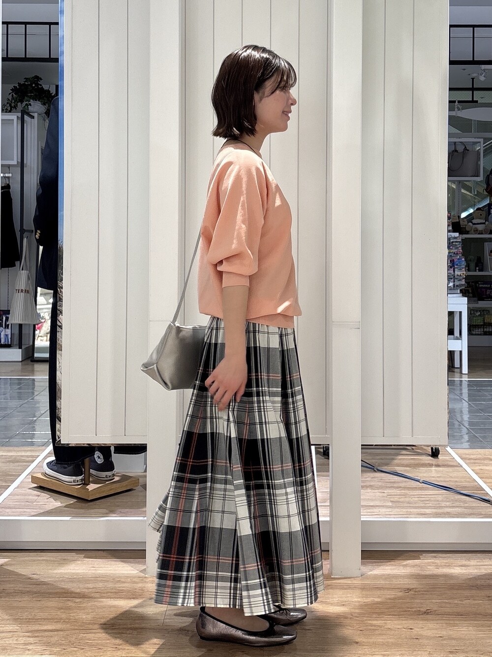 レッド系のスカート、オレンジ系のニット/セーター、シルバー系のショルダーバッグを着用したレディースの春コーディネートの2枚目の写真
