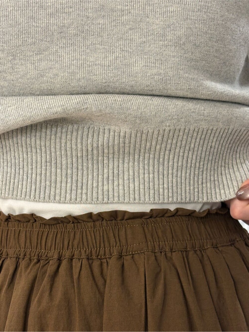 グレー系のニット/セーター、ブラウン系のスカート、ブラック系のブーツを着用したレディースの冬コーディネートの4枚目の写真