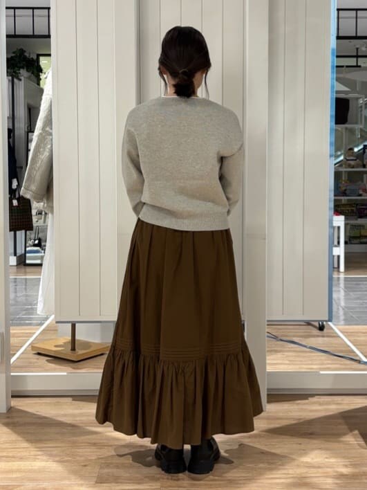 グレー系のニット/セーター、ブラウン系のスカート、ブラック系のブーツを着用したレディースの冬コーディネートの2枚目の写真