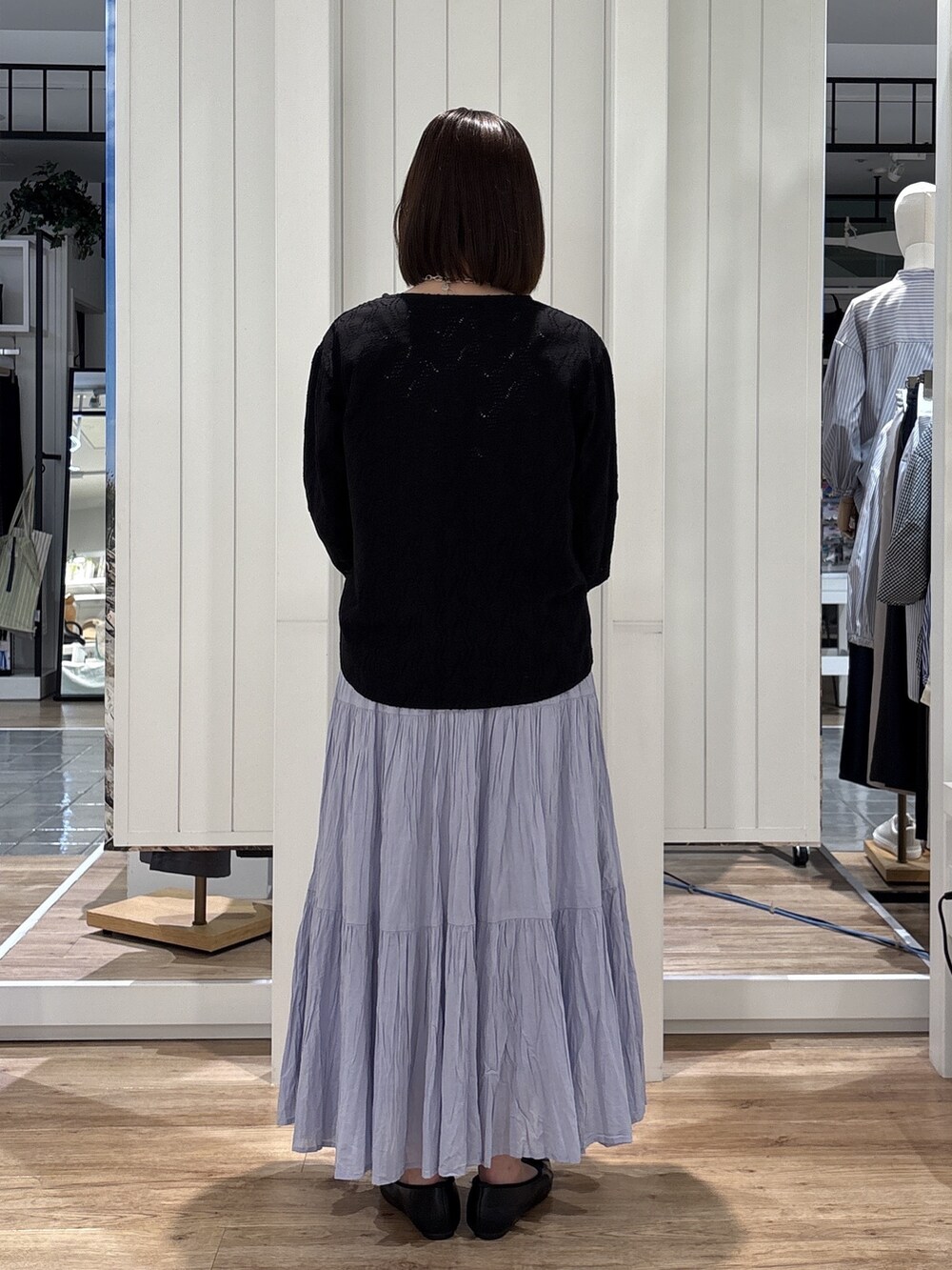 ブルー系のスカート、ブラック系のパンプス、シルバー系のトートバッグを着用したレディースの春コーディネートの3枚目の写真