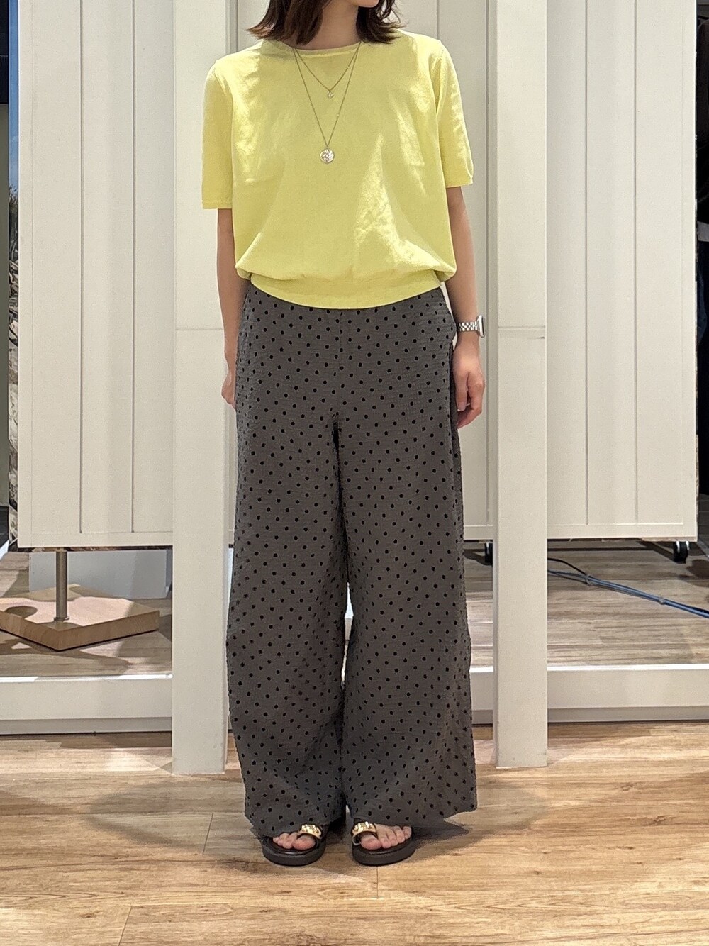 イエロー系のニット/セーター、グレー系のその他パンツ、ブラウン系のサンダルを着用したレディースの夏コーディネートの2枚目の写真